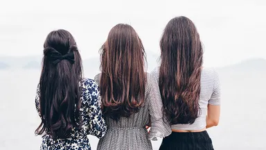 three women with brown hair standing outside